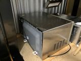 a silver microwave oven sitting on a pallet in a room
