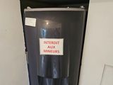 a black refrigerator with a sign on it in the corner of a room