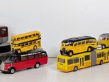 several toy buses are lined up in a row on a white surface
