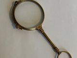 an antique magnifying glass with a metal handle on a white surface