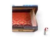 a small wooden box with a red and gold pattern on it