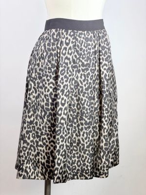 La jupe est confectionnée dans un tissu à imprimé léopard et comporte une ceinture noire.