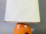 une lampe de table orange surmontée d'un abat-jour blanc