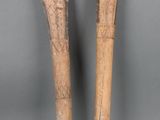 Deux grands bâtons en bois sont posés l'un à côté de l'autre sur une surface grise.
