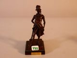 une statue en bronze représentant un homme coiffé d'un haut-de-forme et muni d'une canne