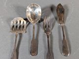 five forks and spoons on a table with a spoon and spoon rest