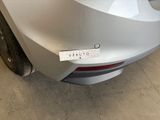 the rear end of a silver car with a sticker on it ' s bumper