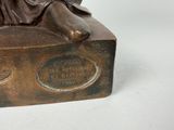 bronze statue of a woman sitting on top of a box
