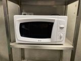 a white microwave sitting on a shelf in a kitchen