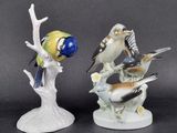 two figurines of birds sitting on a tree branch