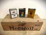 three cans of oil sitting on top of a wooden box