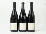 trois bouteilles de vin sont alignées sur une surface blanche