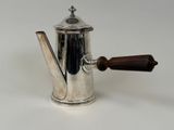a silver coffee pot with a wooden handle on a white surface