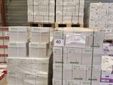 Plusieurs palettes de cartons sont empilées les unes sur les autres dans un entrepôt