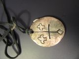 a silver pendant with a cross on it on a black surface