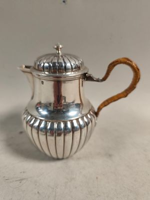 une théière en argent avec une poignée en bois posée sur une table