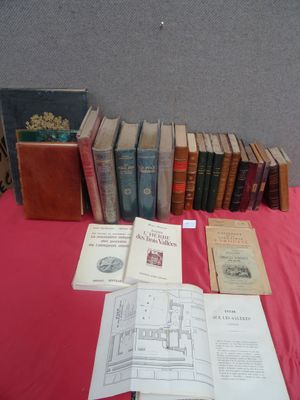 Plusieurs vieux livres sont posés sur une table recouverte d'une nappe rouge.