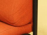 an orange chair with a black frame and a red cushion