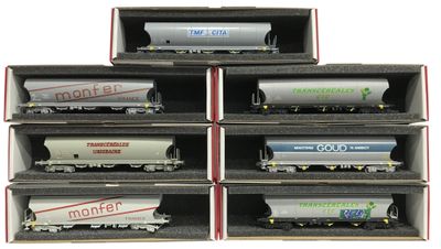 six wagons de train miniature sont empilés dans une boîte posée sur une surface blanche