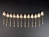 six cuillères en argent alignées sur une surface noire
