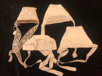 three pieces of white cloth with lace on them on a black background