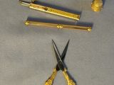 a pair of scissors and a pair of gold scissors on a table