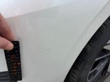 someone is measuring the height of a white car with a ruler