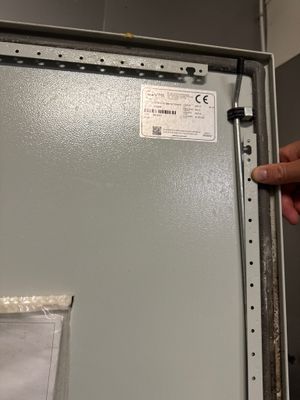 une main tenant un bout de papier devant un réfrigérateur