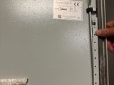 une main tenant un bout de papier devant un réfrigérateur