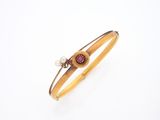 un gros plan sur un bracelet orné d'une perle et d'une pierre rouge