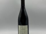 une bouteille de vin posée sur une table à côté d'un mur blanc
