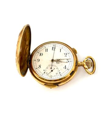 une montre de poche en or posée sur une surface blanche