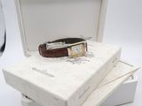 a watch in a box with a glass of wine in the background