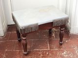 un petit banc orné de franges, placé dans un coin de la pièce