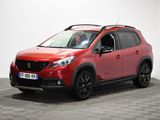 une voiture rouge est garée dans une pièce au sol en damier