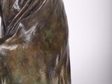 statue of a woman sitting on a chair with her hands on her knees