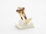 a close up of a gold ring with a pearl and garnets