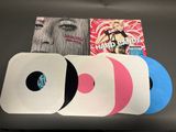 four different colored vinyl records sitting on a table