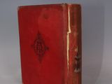 an old red book sitting on top of a white table