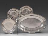 trois plateaux et deux plats en argent sur une table