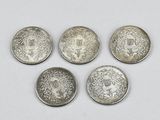 four silver coins with faces on them sitting on a white surface