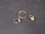 two gold rings and a gold ring on a black surface