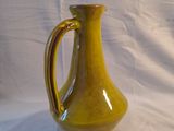 un vase jaune posé sur une surface blanche