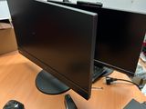 deux écrans posés sur un bureau, avec une souris et un téléphone portable