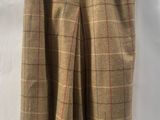 brown plaid pants hanging on a hanger on a white wall