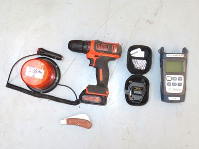 a cordless drill, a cordless charger, a cordless charger, and a cell phone on a table