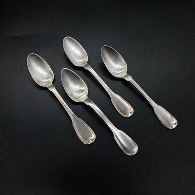 four silver spoons are lined up in a row on a black surface