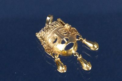 un pendentif en or orné d'une couronne, sur un fond bleu