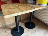 two wooden tables with black metal bases on a wooden floor