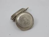 a close up of a silver pocket watch on a white surface